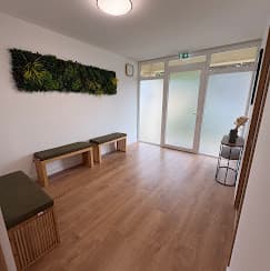 La salle d'attente du cabinet, avec ses banquettes en bois et son mur végétal